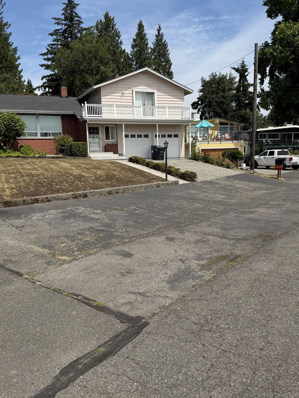 A faded gray shared driveway with cracking across the surface before sealcoating.