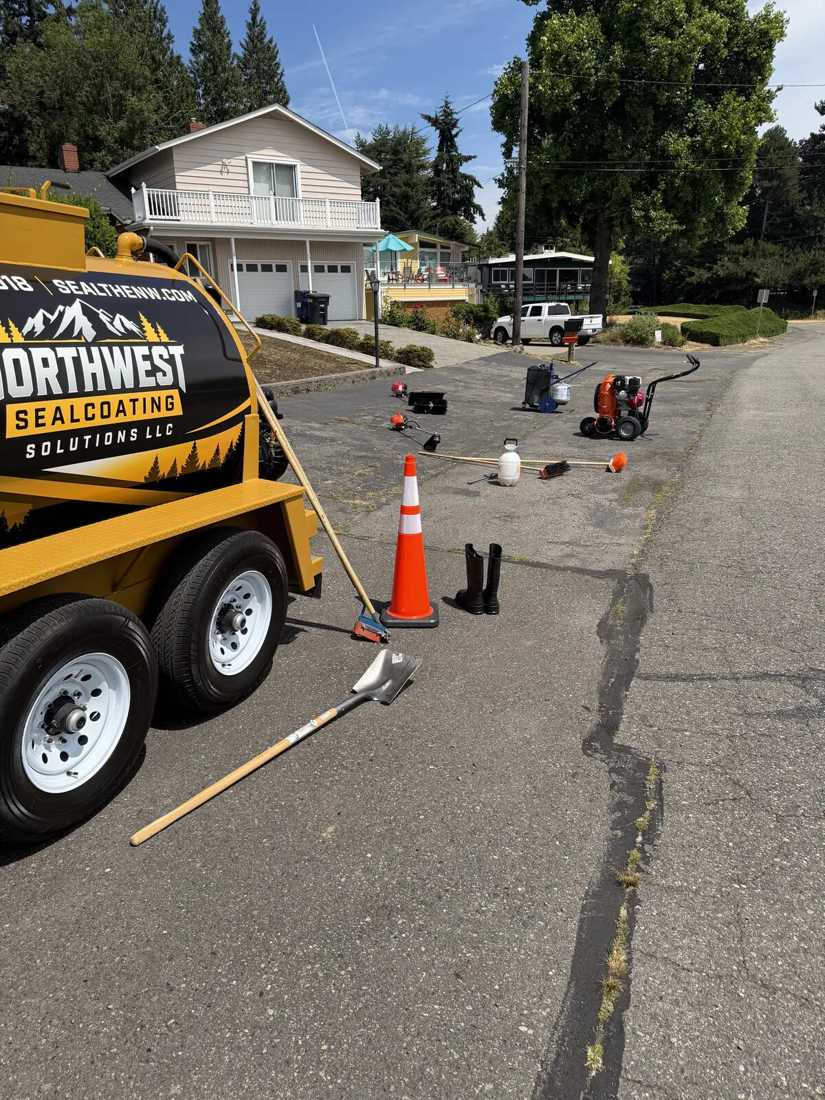 The Northwest Sealcoating trailer on site with cones out and squeegees laid out.