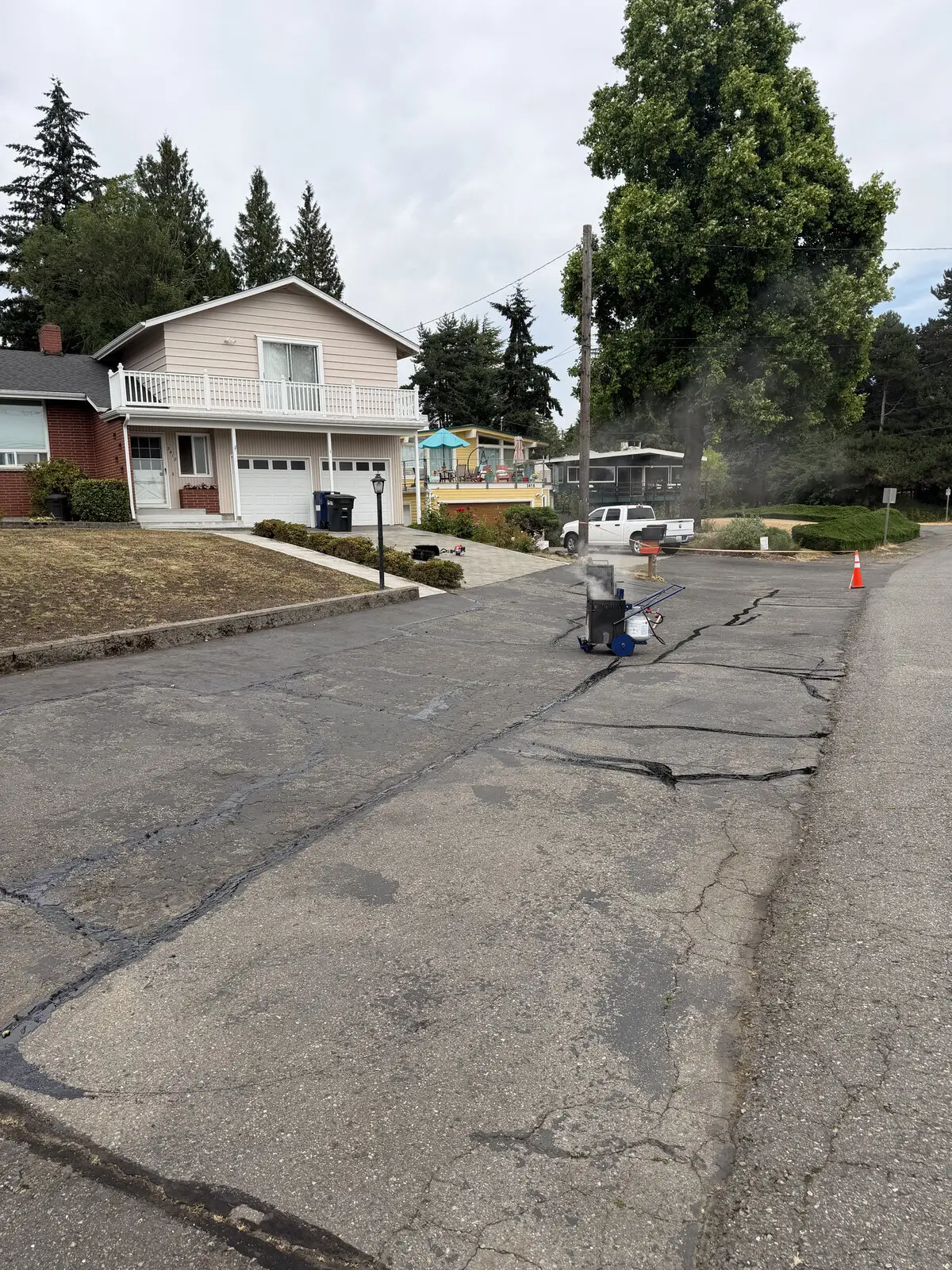 Surface prep underway, blowing dust and debris off the asphalt before sealer goes down.