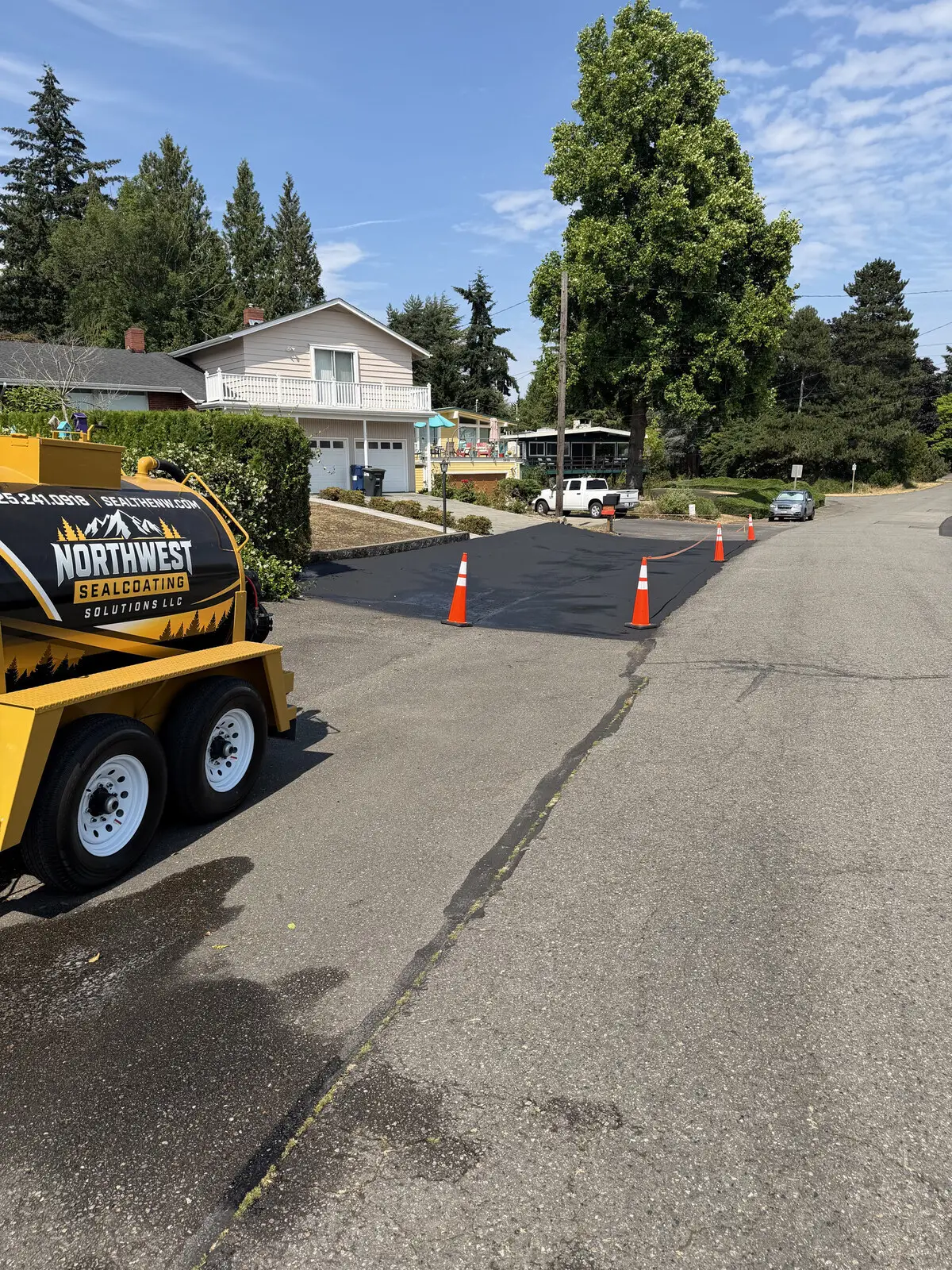 Sealing in progress: a jet-black freshly sealed lane beside untreated gray asphalt.
