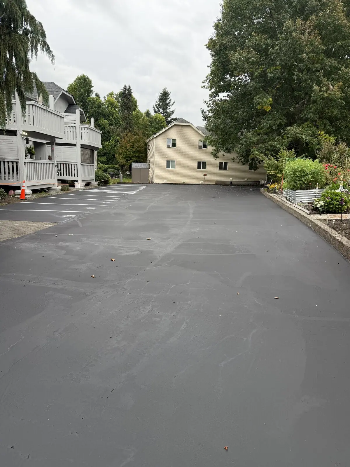 An apartment complex parking lot freshly sealcoated and restriped, with crisp white stall lines.